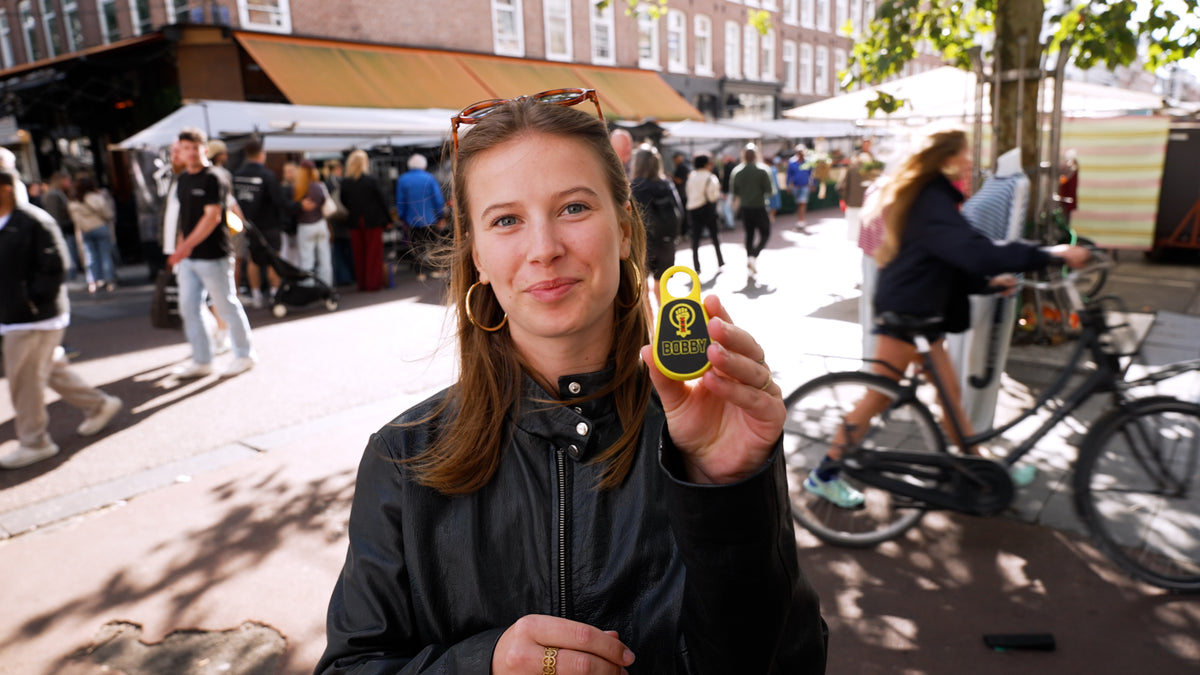 Vrouw met een geel BOBBY persoonlijk alarm op de Albert Cuypmarkt