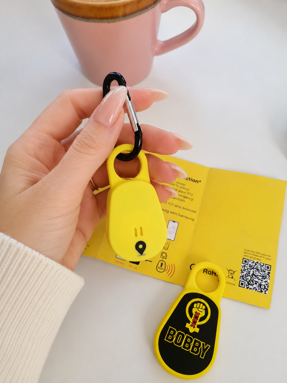 Bobby persoonlijk alarm met bluetooth SOS-functie in de hand van een vrouw.